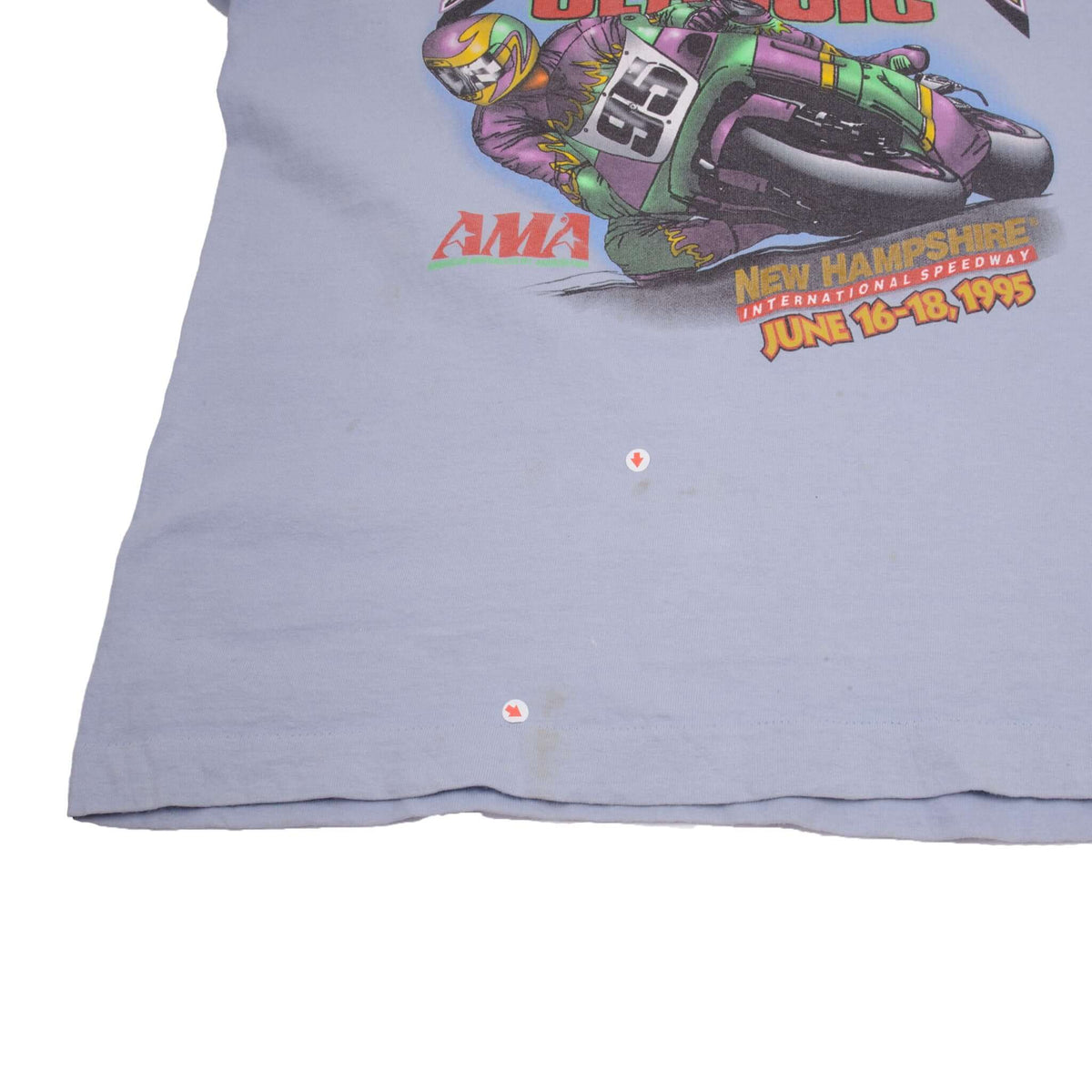 Lower front of light blue racing T-shirt with two small marked spots below the graphic