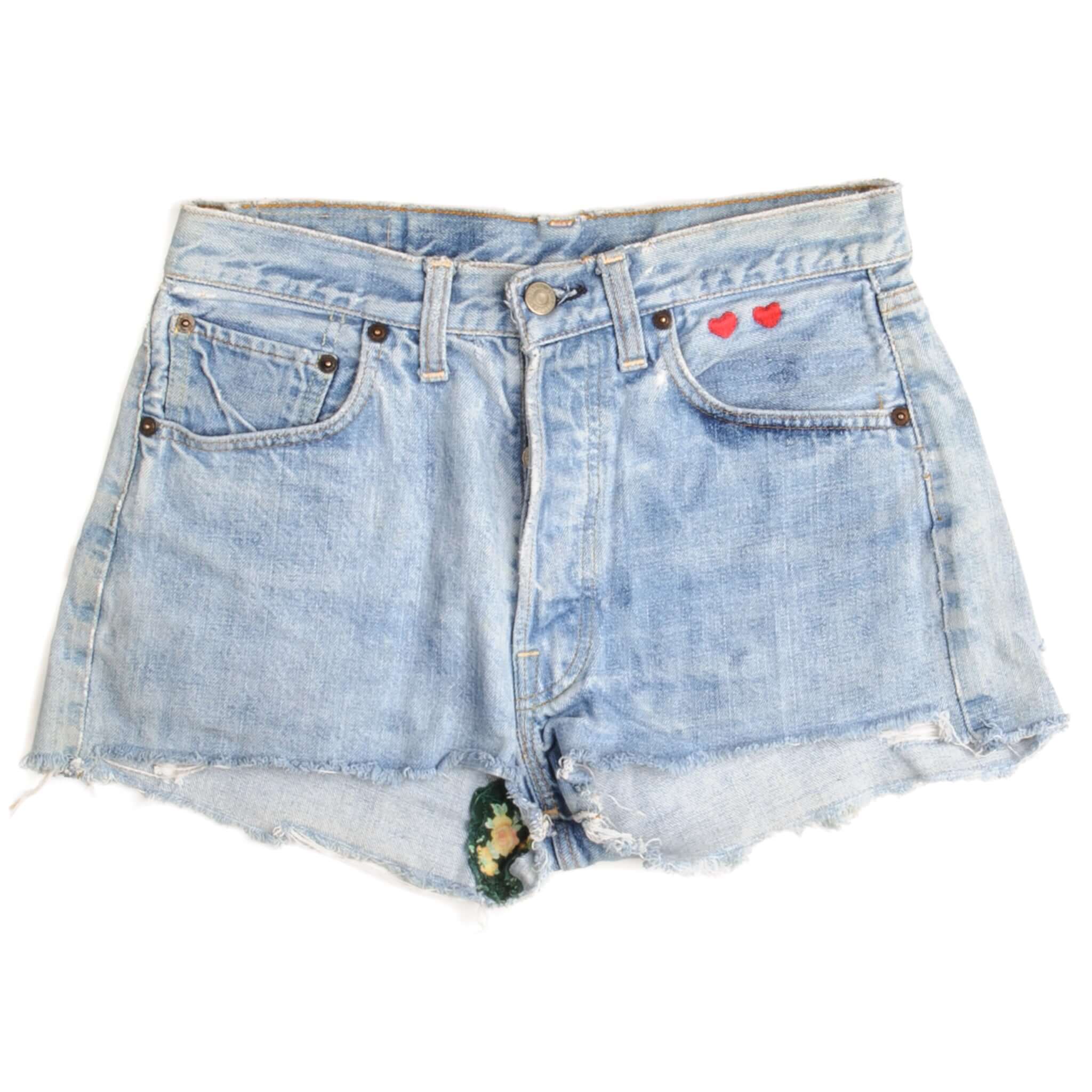 Front of light blue Levi's 501 denim shorts with raw hems and red heart embroidery