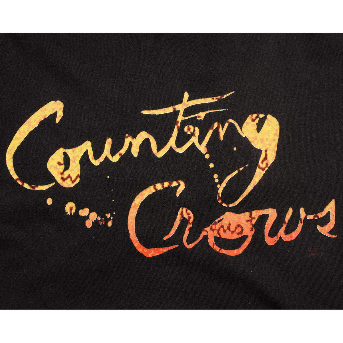 Close-up of yellow and orange Counting Crows script print on black fabric