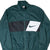 Front detail of green Nike windbreaker with black-and-white chest panel and Swoosh