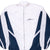 Front close-up of white and navy Nike windbreaker with zip closure and embroidered chest logo
