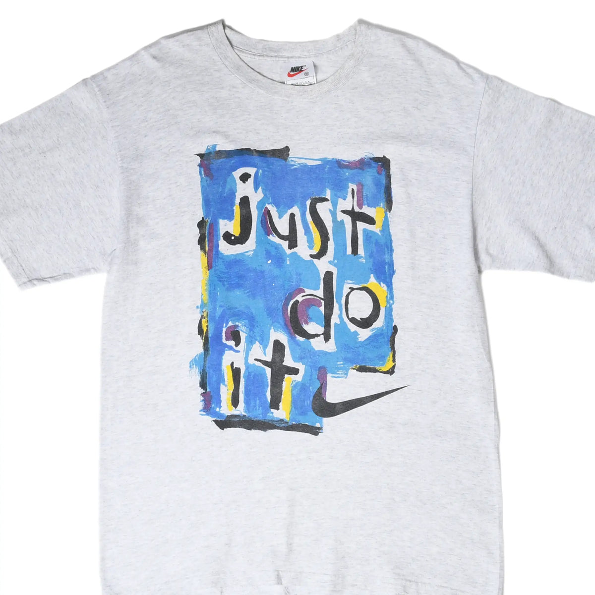 Front close-up of grey Nike T-shirt with blue painted Just Do It graphic and black Swoosh