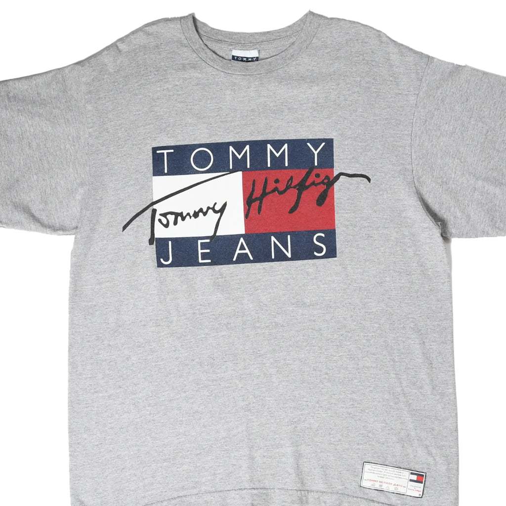 Front close-up of grey Tommy Jeans T-shirt with navy, white and red spellout graphic and hem label
