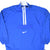 Front of blue Nike pullover windbreaker with white quarter zip and Swoosh pocket