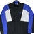 Front close view of black Nike windbreaker with blue sleeves, white panels, and embroidered Swoosh