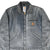 Front detail of faded gray Carhartt Detroit jacket with zip chest pocket and logo patch