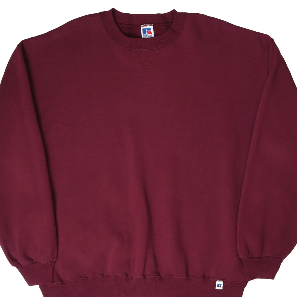 Front view of burgundy Russell Athletic crewneck sweatshirt with ribbed cuffs, hem logo tag, and V-stitch collar