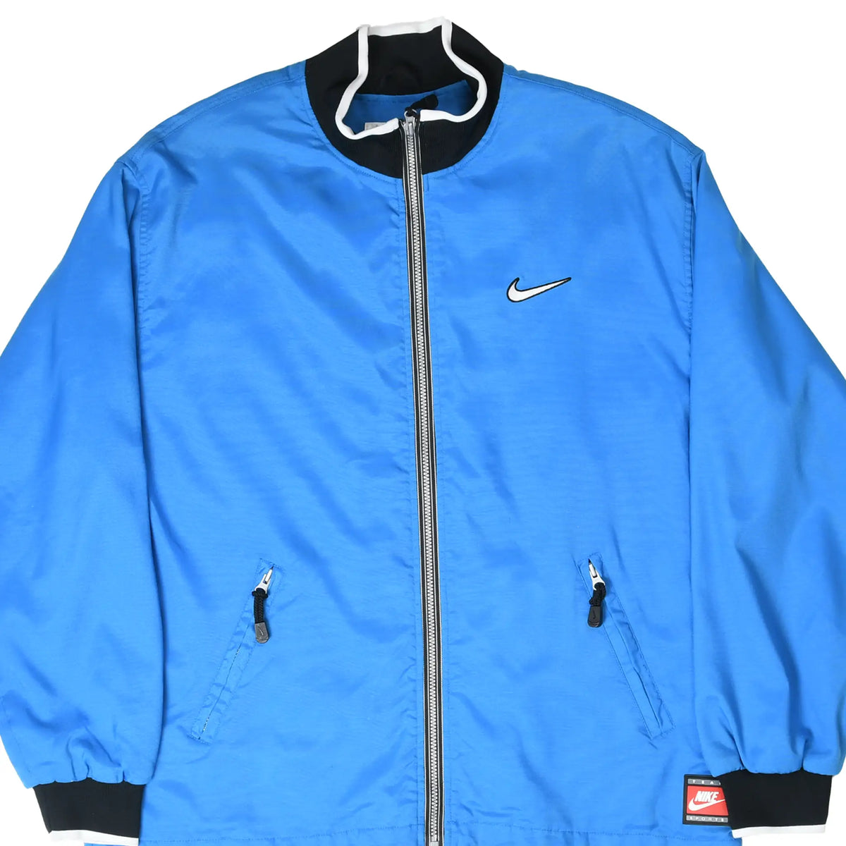 Front of blue Nike windbreaker jacket with white Swoosh, zip pockets, and black collar and cuffs