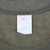 Close-up of faded interior neck tag and collar stitching on olive green T-shirt