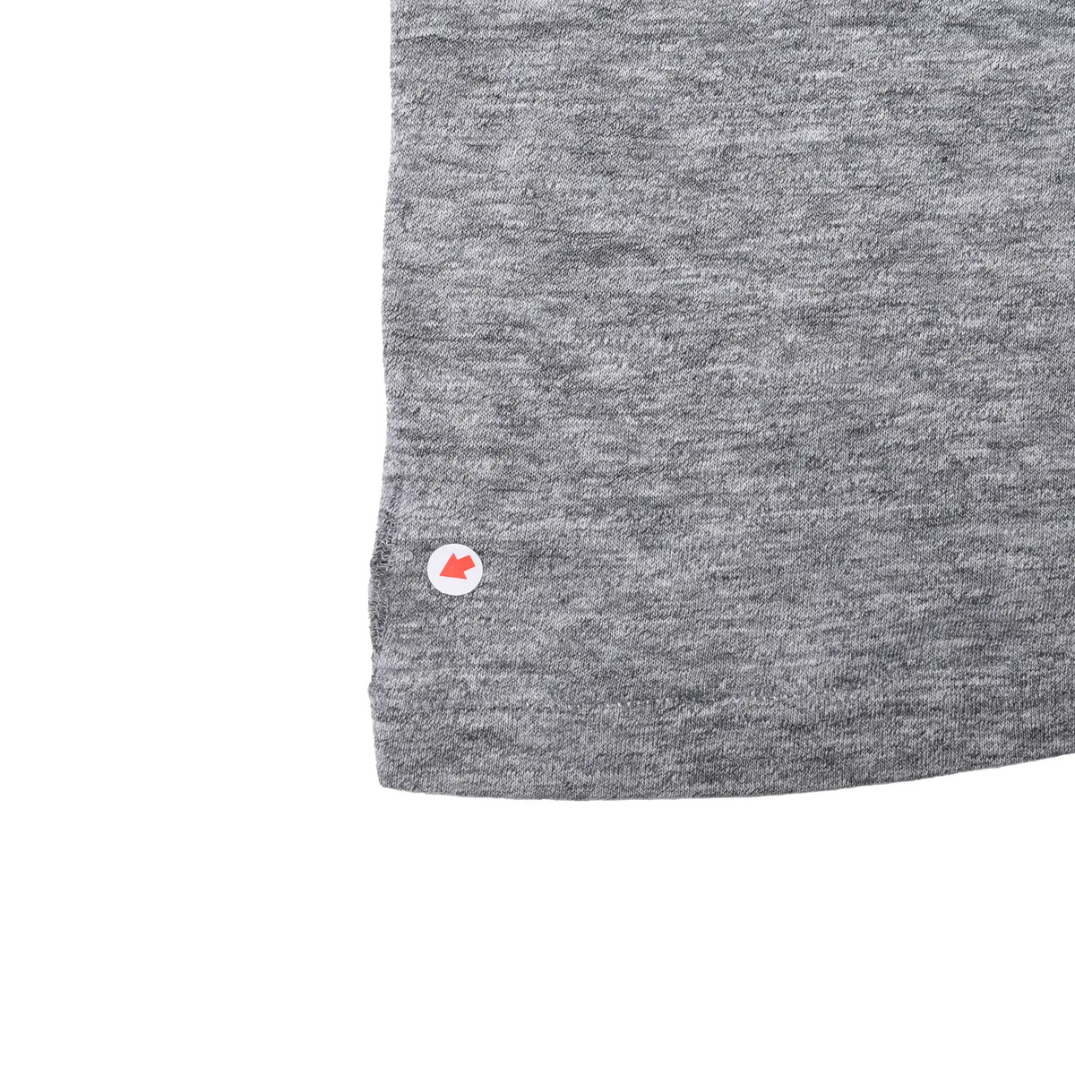 Close-up of gray T-shirt lower hem with arrow marking a small fabric spot