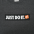 Close-up of white Just Do It lettering and orange Nike logo on black chest print