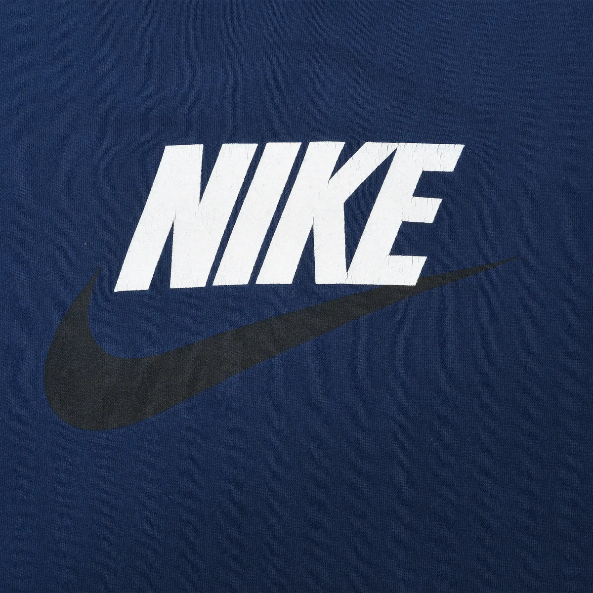 Close-up of white Nike spellout and black Swoosh print on navy blue fabric