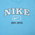 Close-up of white Nike spellout, Swoosh, and Est. 1972 print on light blue T-shirt