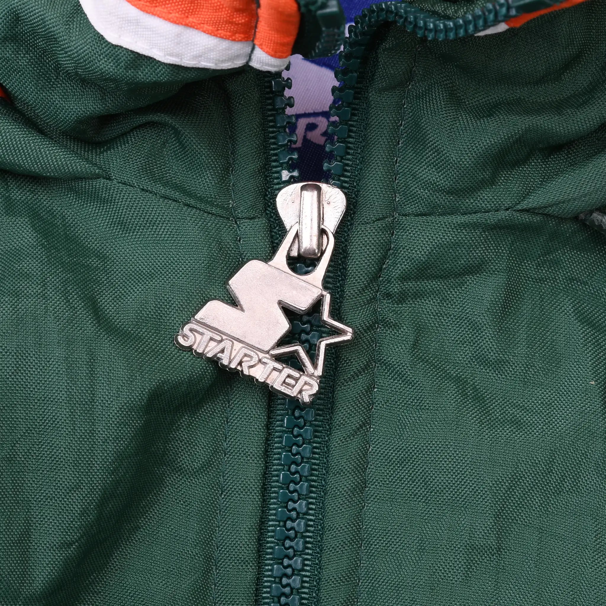 Close-up of metal Starter logo zipper pull on green jacket