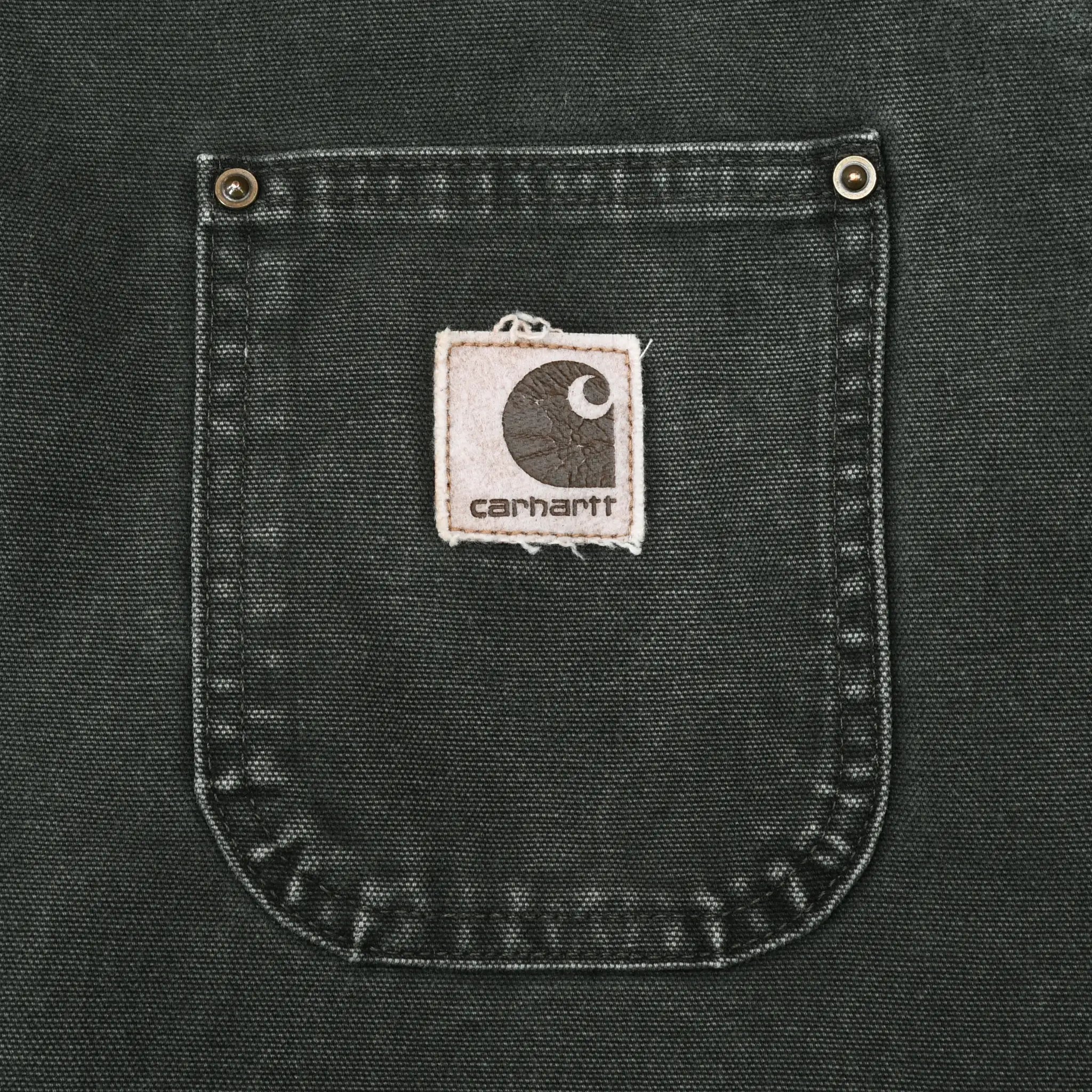 Close-up of chest pocket with stitched Carhartt logo patch and metal rivets