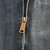 Close-up of brass-tone Carhartt zipper pull on faded gray fabric