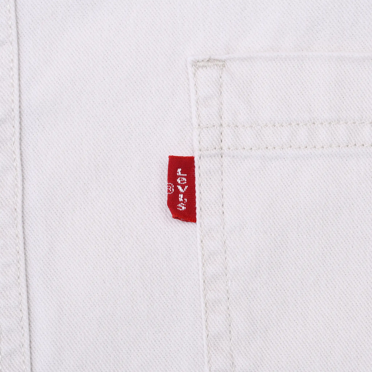Close-up of red Levi's tab stitched beside chest pocket on white denim shirt