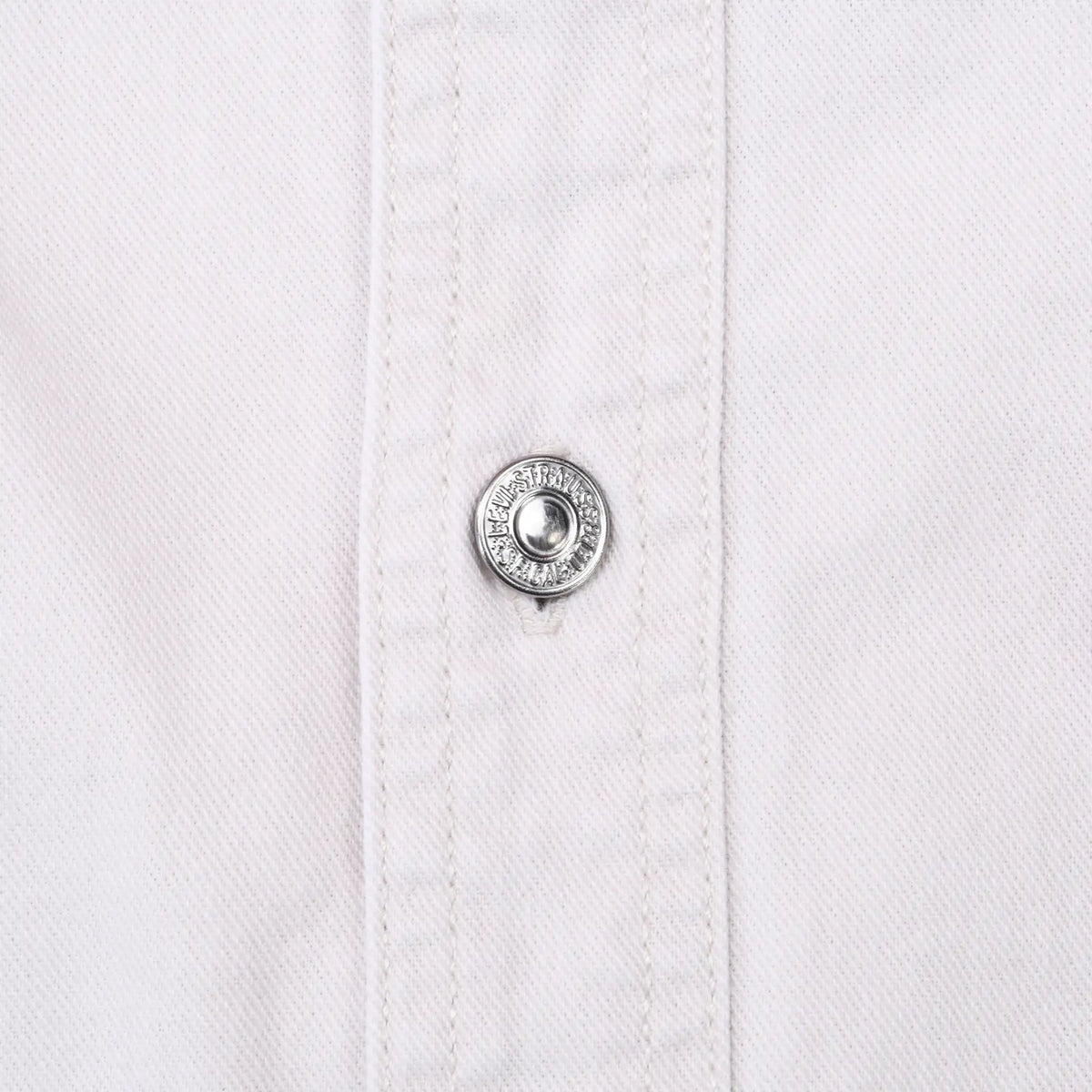 Close-up of engraved silver-tone Levi's snap on white denim shirt placket