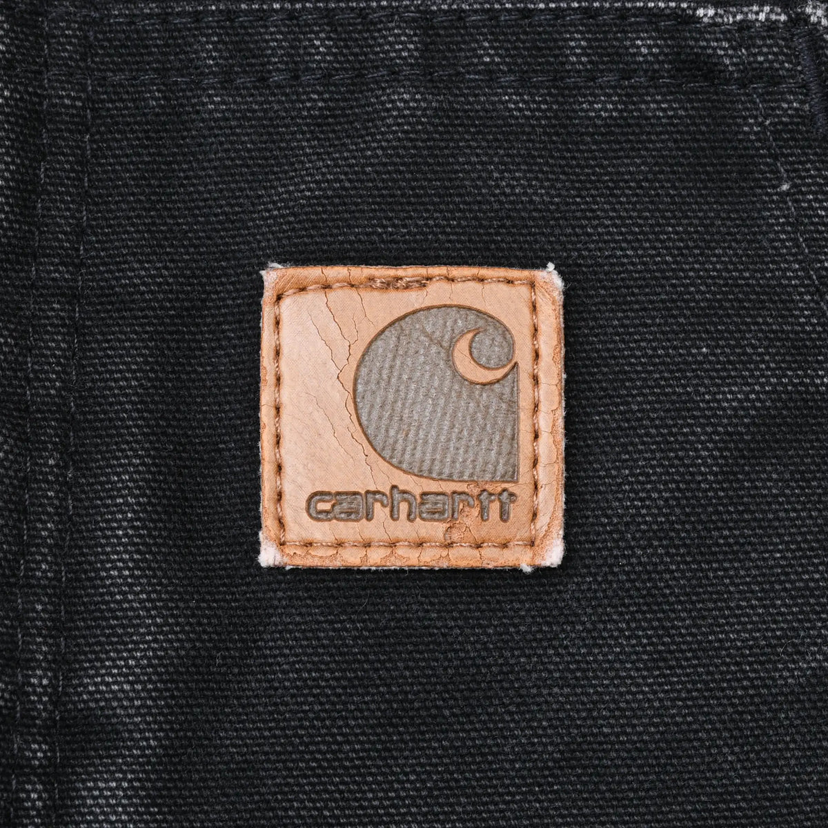 Close-up of Carhartt logo patch stitched to black jacket pocket