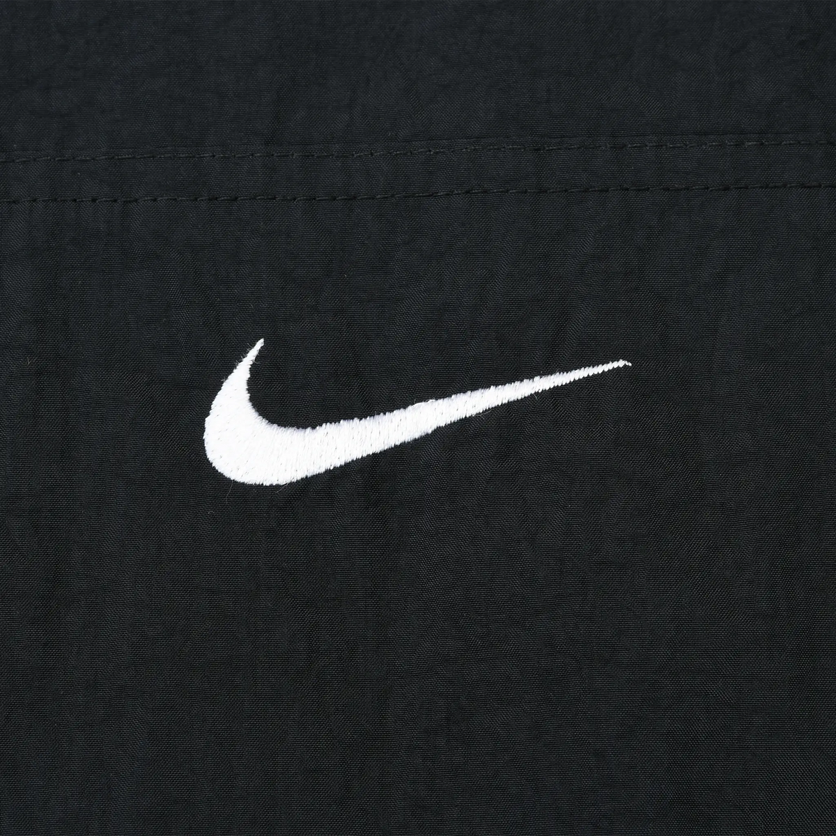 Close-up of white Nike Swoosh embroidery on black fabric