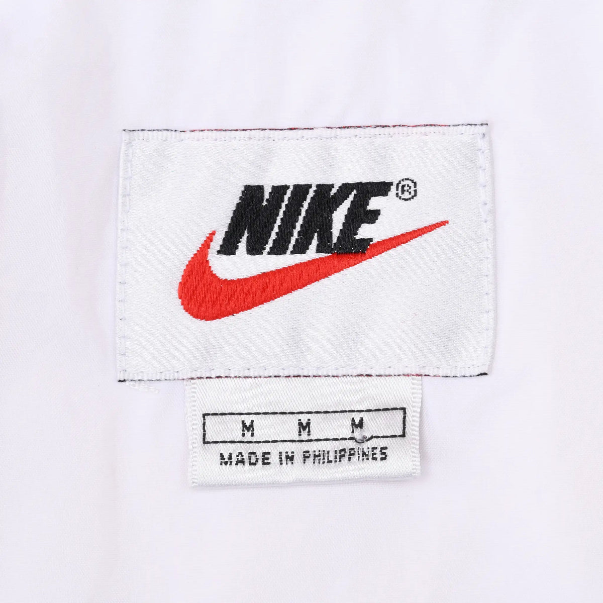 Close-up of white Nike neck label with black logo and red Swoosh
