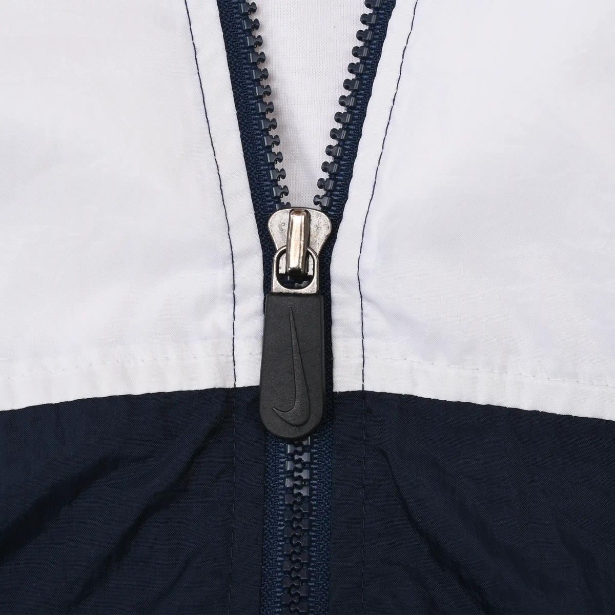 Close-up of navy front zipper and Nike Swoosh pull on white and navy panels
