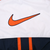 Close-up of large orange Nike Swoosh graphic outlined in navy on the white back panel