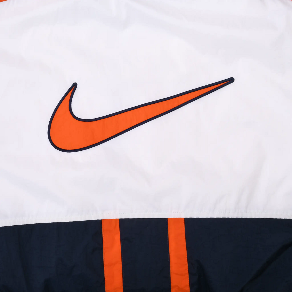 Close-up of large orange Nike Swoosh graphic outlined in navy on the white back panel