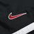 Close-up of red and white embroidered Nike Swoosh on black jacket shell