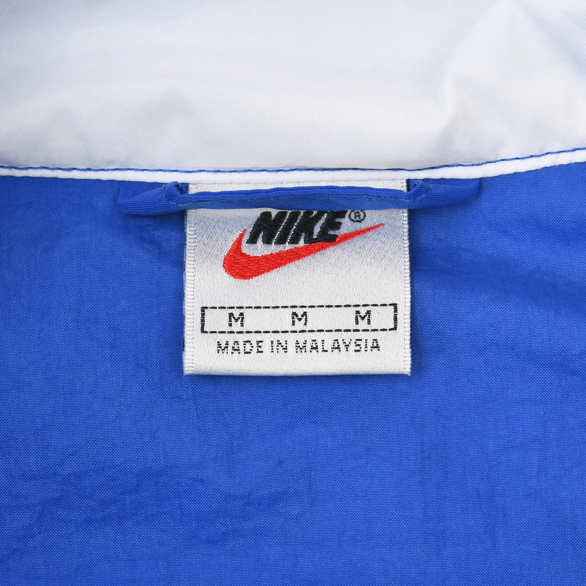 Nike neck label showing size medium inside blue pullover windbreaker