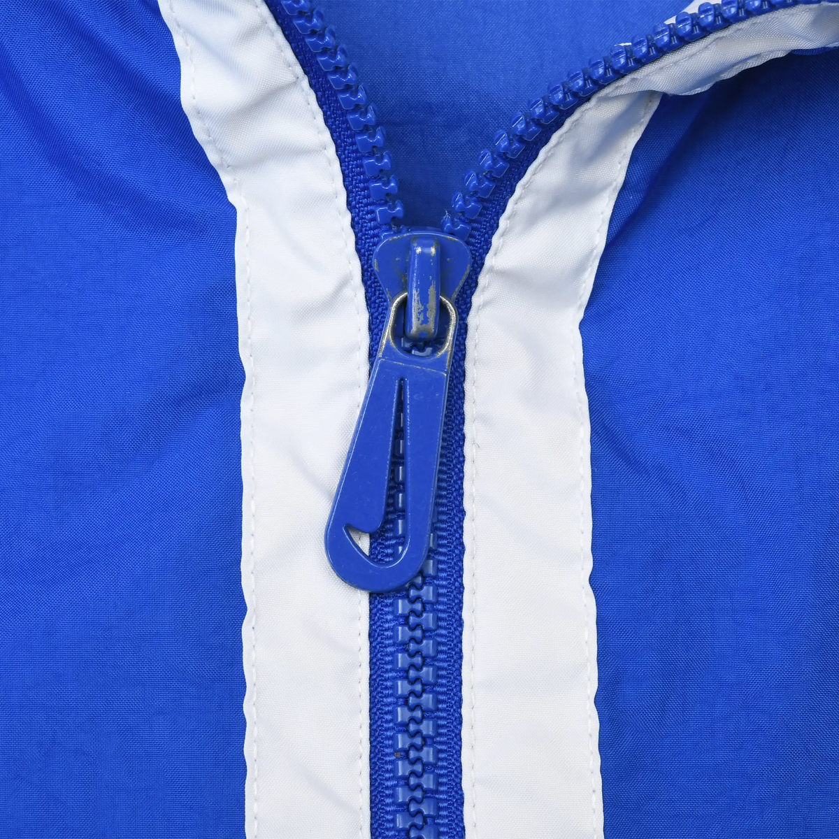 Close-up of blue quarter zipper and white trim on Nike pullover windbreaker