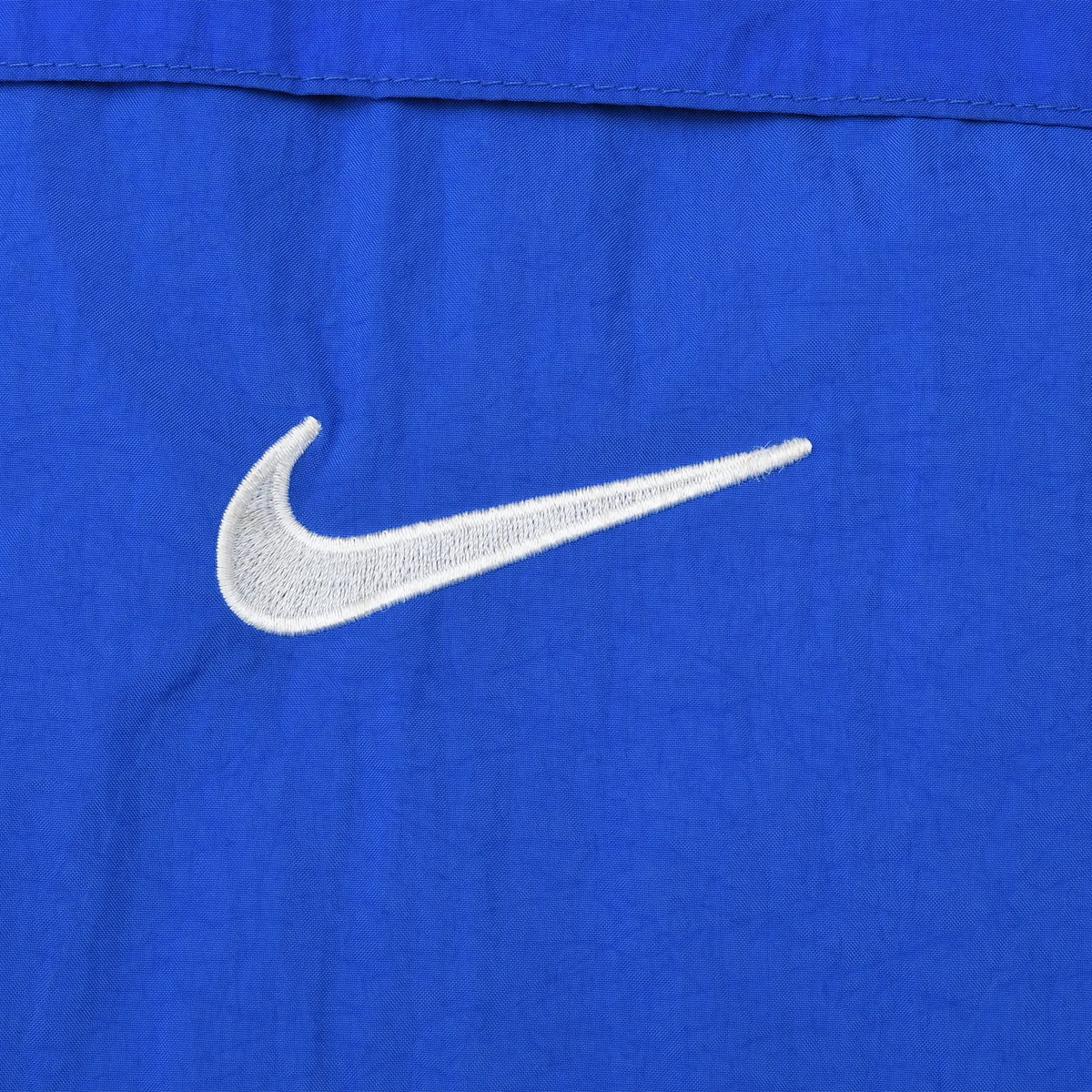Close-up of white Nike Swoosh embroidery on blue front pouch pocket