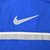 Close-up of large white Nike Swoosh embroidery and stripe on blue jacket back