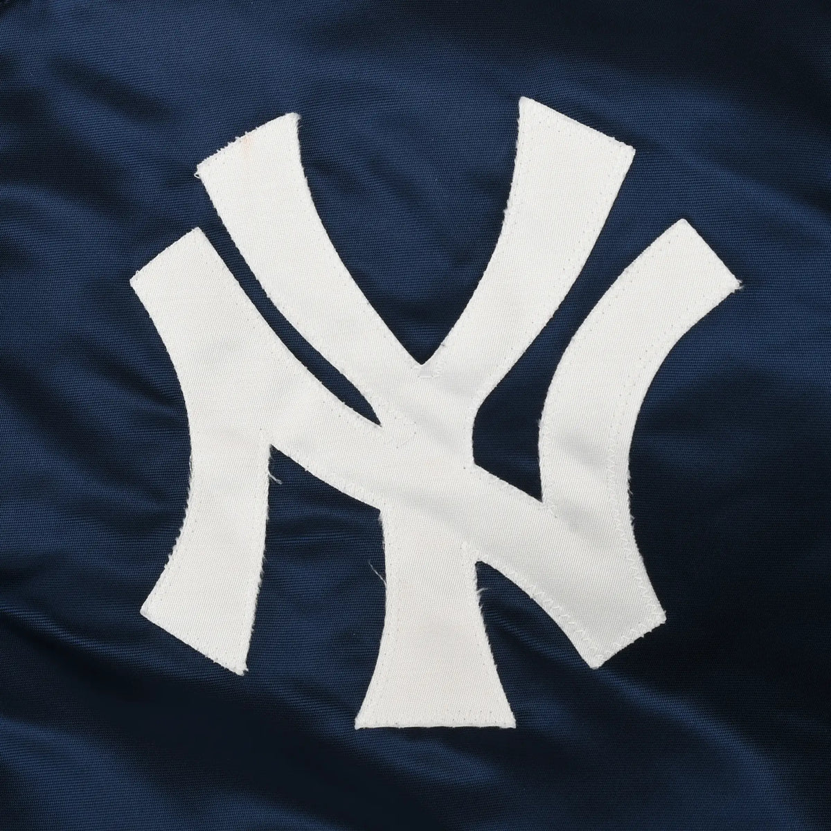 Close-up of white New York Yankees NY logo on navy jacket