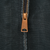 Close-up of brass-tone Carhartt zipper pull on black jacket fabric