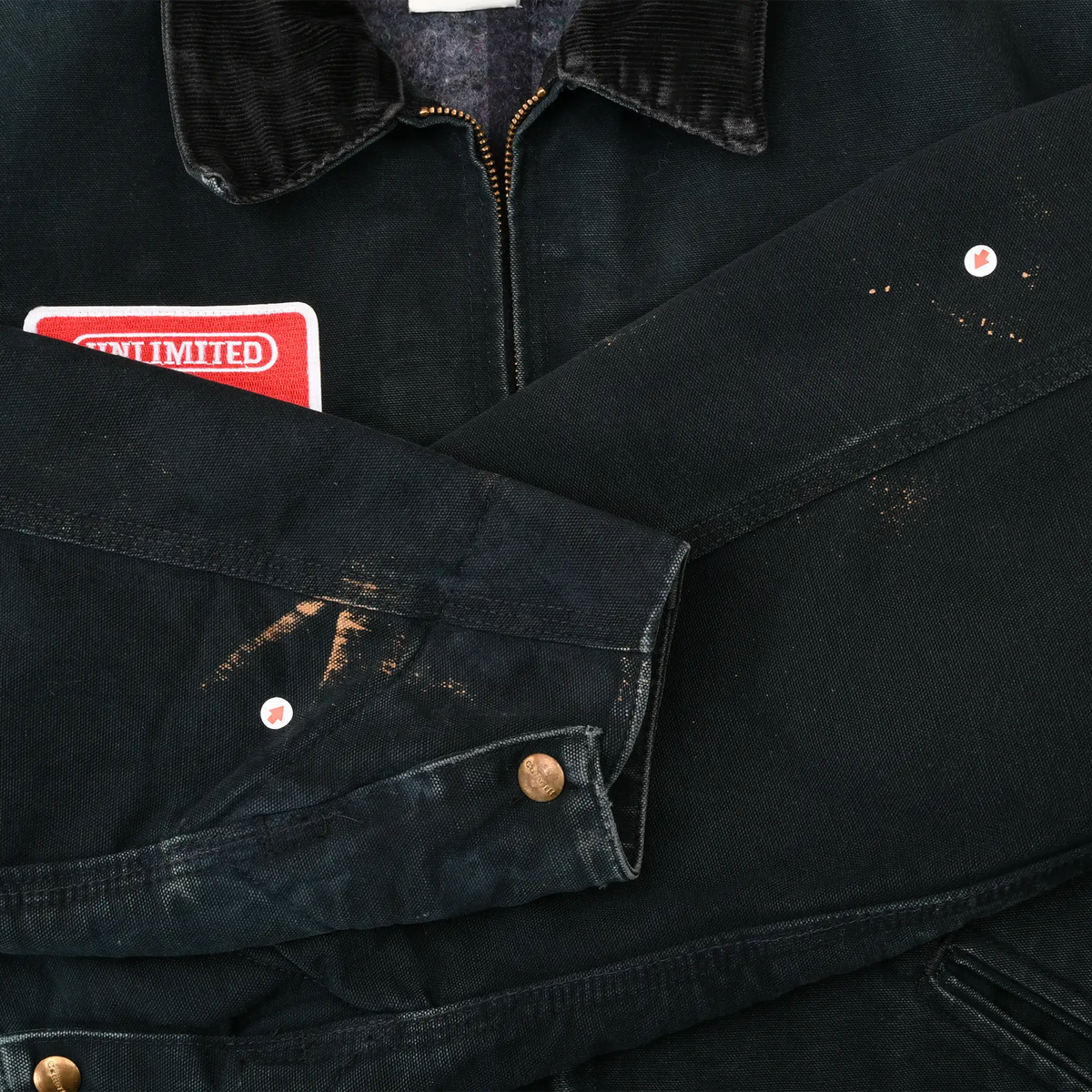 Close-up of jacket sleeves and cuffs showing scuffs, paint spots, and brass-tone snaps