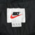 Nike neck label with red Swoosh and XL size tag inside black jacket