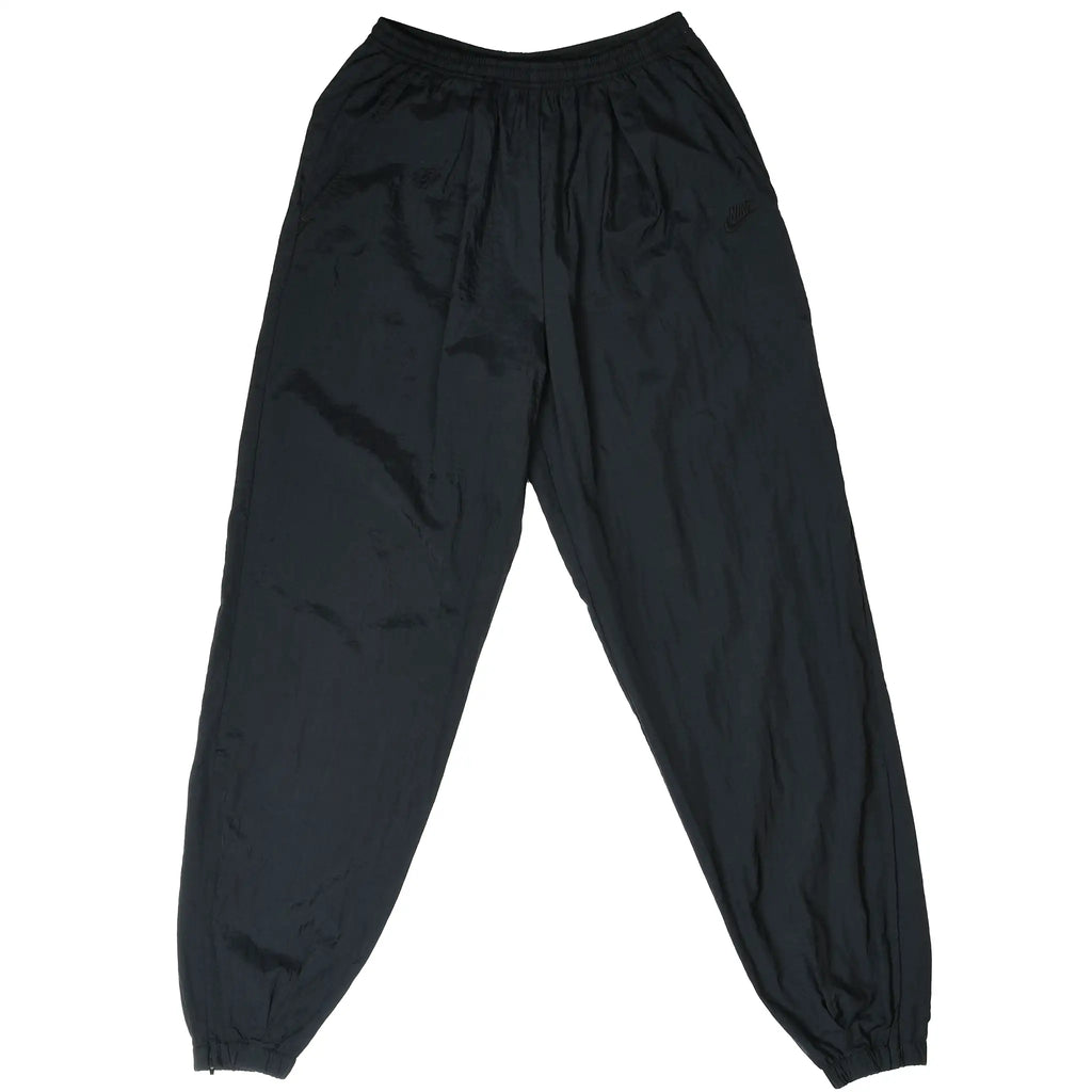 Front of black Nike nylon track pants with elastic waist and cuffs