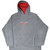 Front of grey Nike fleece hoodie with red hood lining, embroidered Swoosh, sleeve logo, and kangaroo pocket