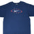 Front of blue Nike T-shirt with white Swoosh, red oval, blue stripes, and yellow stars