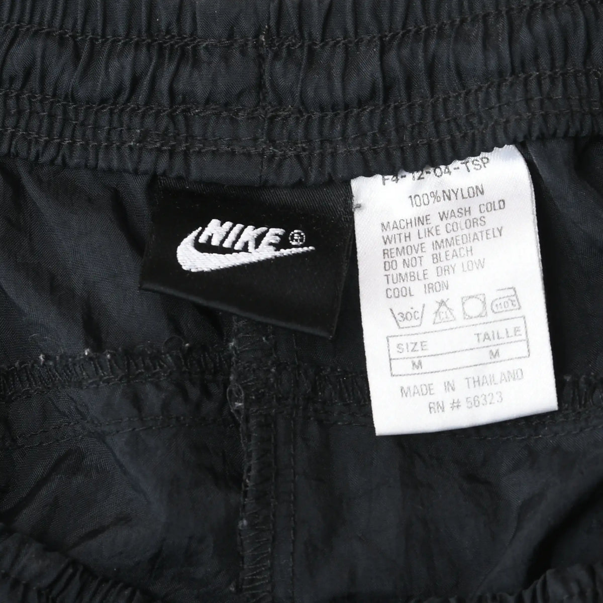 Nike waistband tag and care label showing 100% nylon and size medium