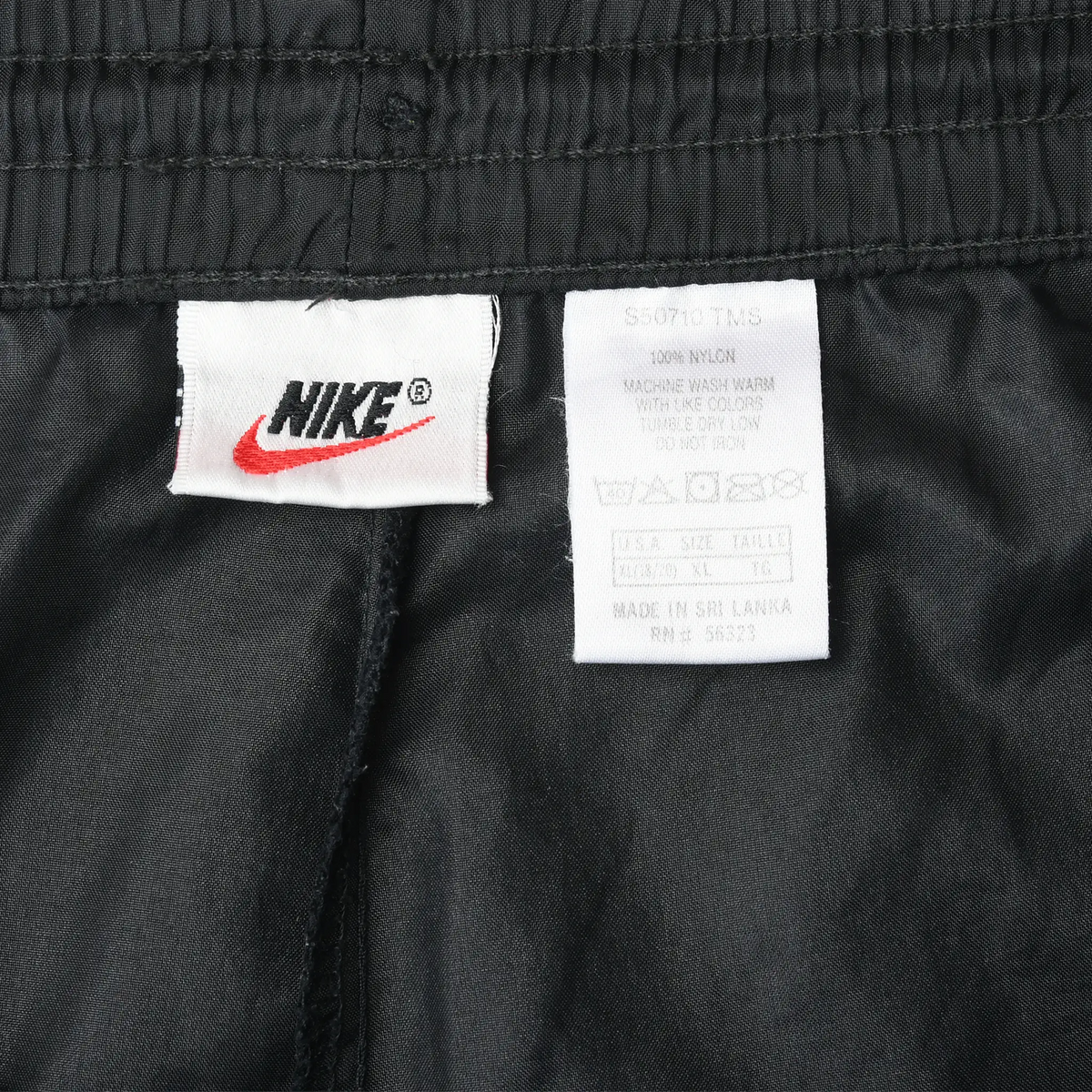Interior Nike logo and care labels at the waistband of black track pants
