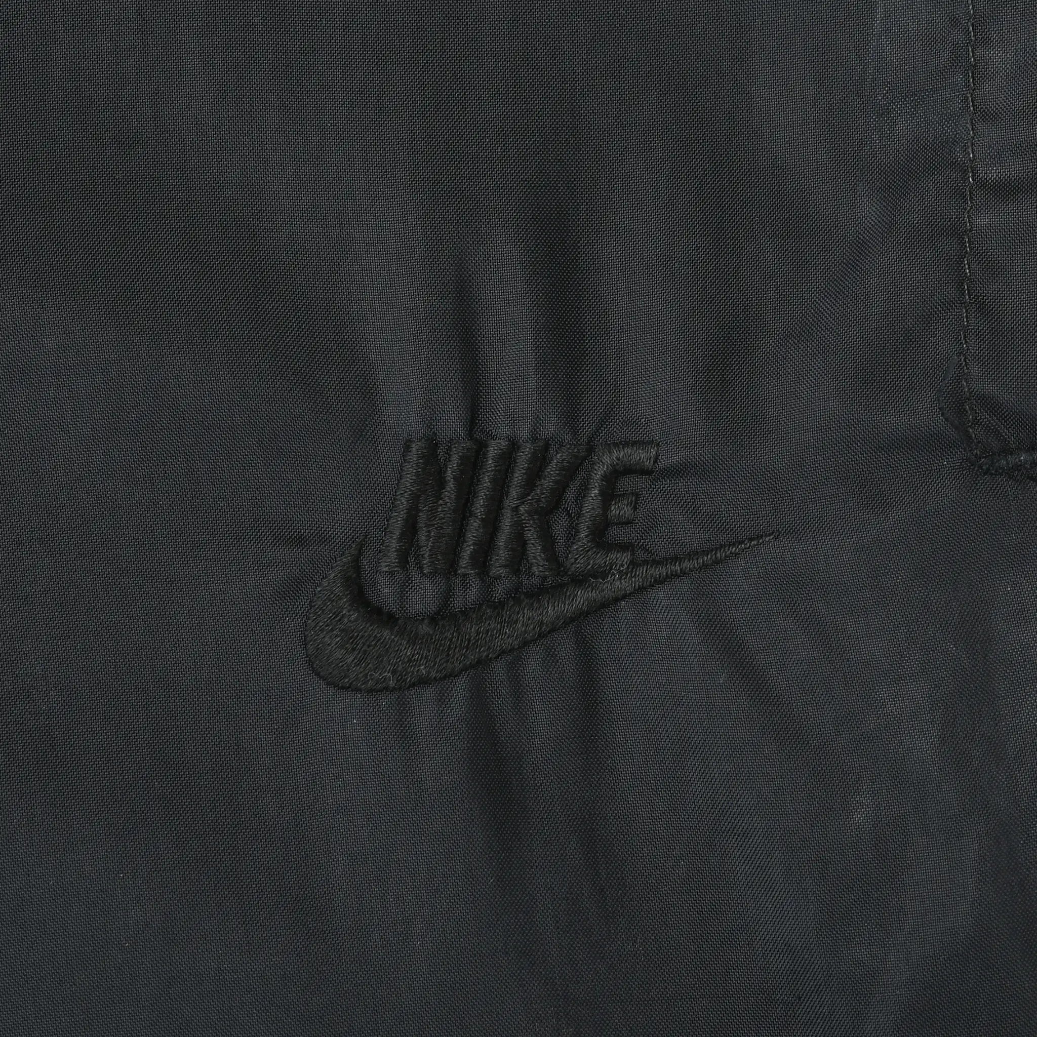 Close-up of black Nike logo embroidery on the track pants