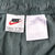 Close-up of Nike waistband label and care tag inside dark green track pants