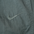Close-up of tonal Nike Swoosh embroidery on dark green track pants