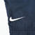 Close-up of white Nike Swoosh embroidery on navy blue track pants