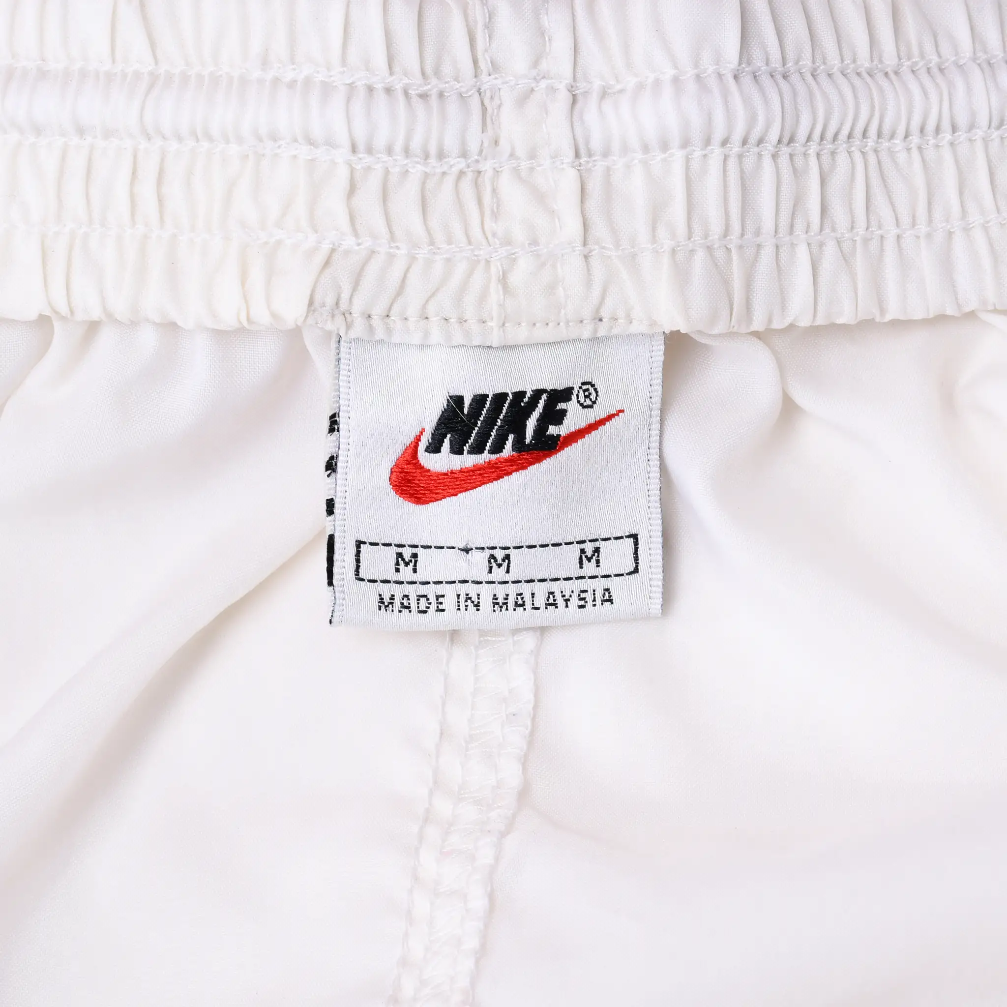 Nike waistband label with black logo, red Swoosh, and medium size marking