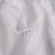 Close-up of white Nike Swoosh embroidery on white track pants