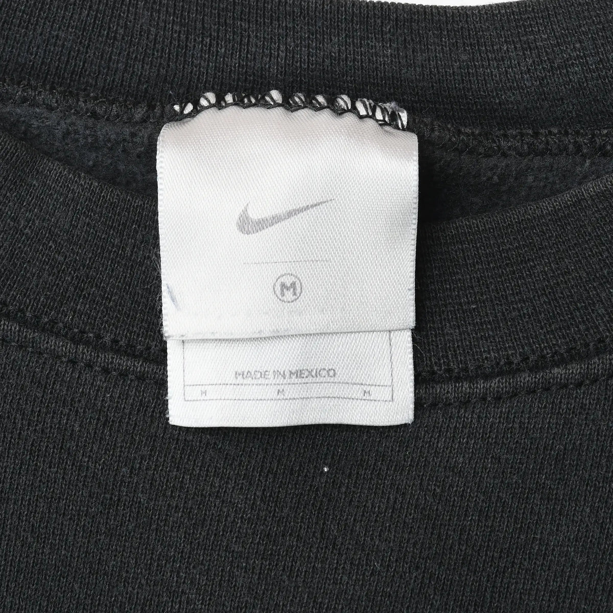 Close-up of white Nike neck label inside black sweatshirt