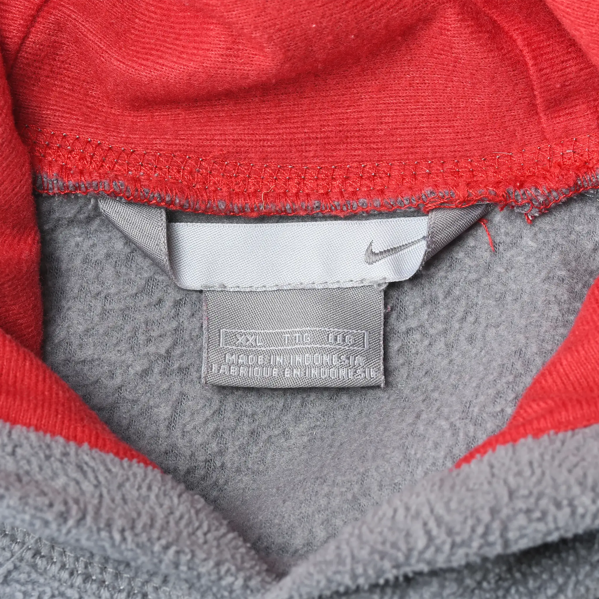 Close-up of Nike neck label inside grey fleece hoodie with red hood lining